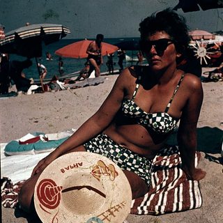 Woman relaxing on beach with hat.