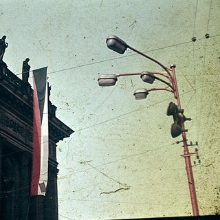 Vintage photo of traditional Asian building with flags and street lamps.