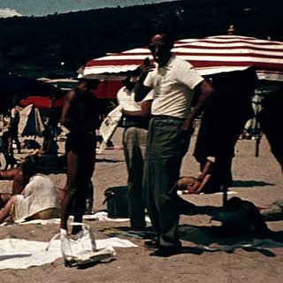 Beach scene with people relaxing under umbrellas.