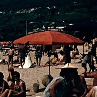 Beach scene with people relaxing under umbrellas.
