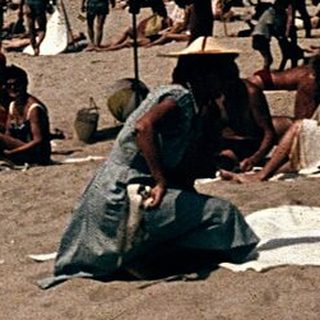 Beach scene with people relaxing under umbrellas.