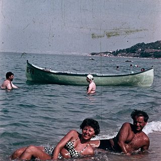 People enjoying beach and sea in vintage boat setting.
