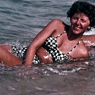 People enjoying beach and sea in vintage boat setting.