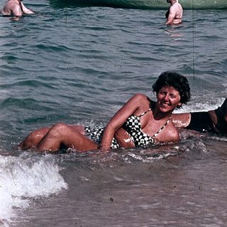 People enjoying beach and sea in vintage boat setting.