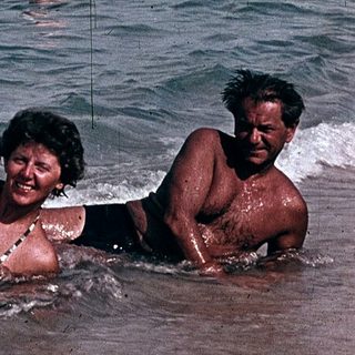 People enjoying beach and sea in vintage boat setting.