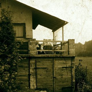 Vintage wooden outbuilding with elevated porch and storage shed.