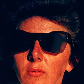 Person wearing sunglasses and light-colored shirt.