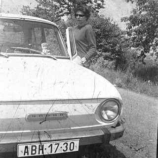 Vintage car with woman leaning in doorway.