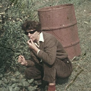 Child sitting on barrel in garden, using early telephone.