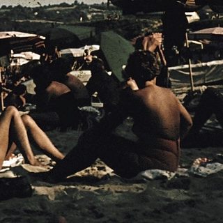 Beach scene with people relaxing under striped umbrellas.