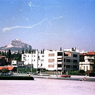 Urban scene with residential buildings, mountain backdrop, clear sky.