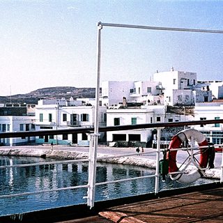 Coastal town with white buildings, waterfront railing, and lifebuoy.