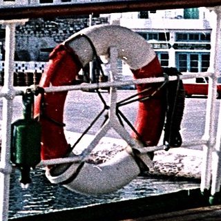Coastal town with white buildings, waterfront railing, and lifebuoy.