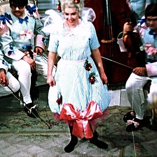 A woman in vintage costume dances on stage with a band.