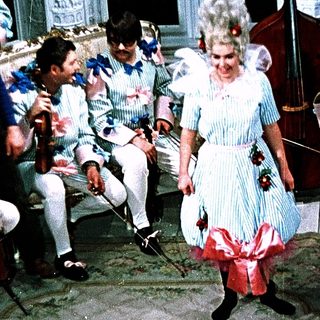 A woman in vintage costume dances on stage with a band.