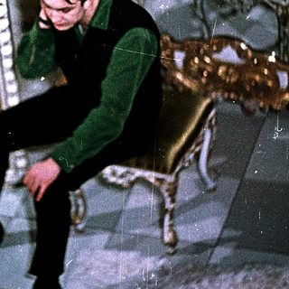 Young man sitting on floor in luxurious room, talking on phone.