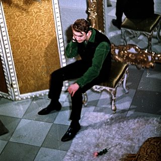 Young man sitting on floor in luxurious room, talking on phone.