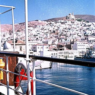 Coastal city with harbor and hilltop church.