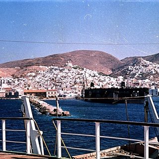 Coastal town nestled by sea with hills.