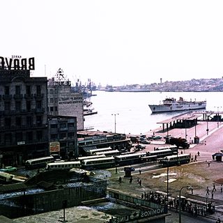 Historic port city with vintage ferry, trams, and waterfront buildings.