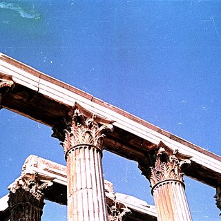 Ancient Greek-style Corinthian columns under clear sky.
