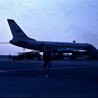 Airport scene with person walking near parked Tupolev jet.