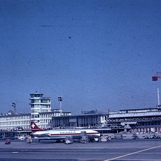 Airport terminal with Swissair plane and control tower.