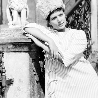 Elegant woman posing beside a stone lion statue.