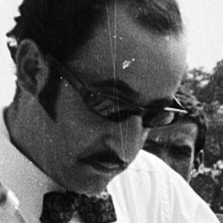 Two people adjusting a man's tie outdoors.