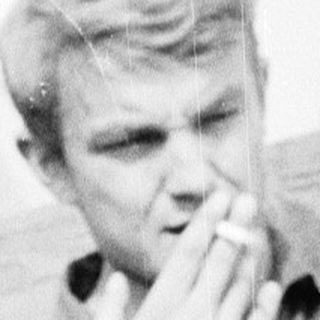 Young man talking on a vintage phone outdoors.