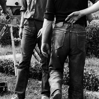 Film crew operating vintage camera outdoors.