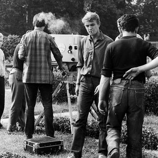 Film crew operating vintage camera outdoors.