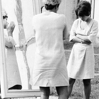 Three women examining a large mirror outdoors.