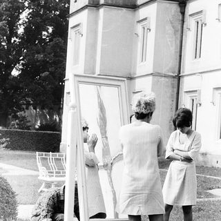 Three women examining a large mirror outdoors.