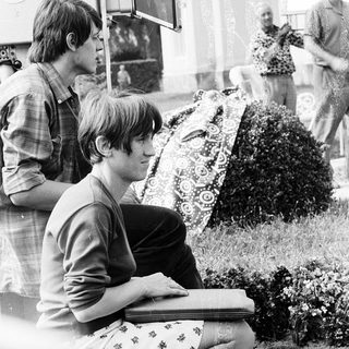 Young man reading book outdoors in 1960s.