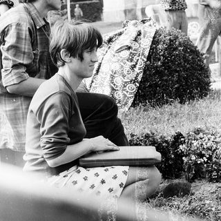 Young man reading book outdoors in 1960s.