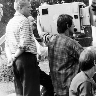 Film crew operating vintage camera outdoors.
