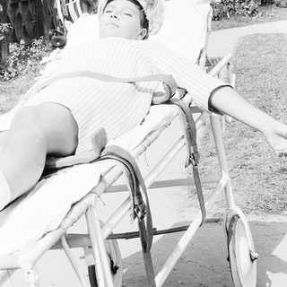 Child peacefully sleeping in a baby carrier outdoors.