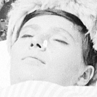Child peacefully sleeping in a baby carrier outdoors.