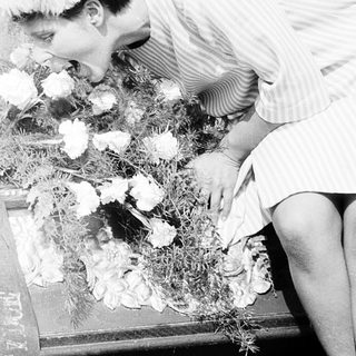 Person placing flowers on a casket.