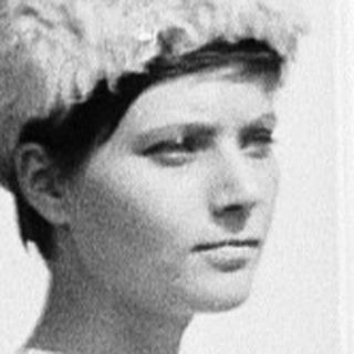 Woman in 1960s-style dress and hat near open door.