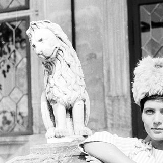 Elegant woman posing with lion statue.