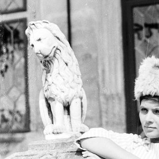 Woman in vintage costume posing with lion statue.