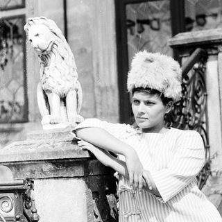 Woman in vintage costume posing with lion statue.
