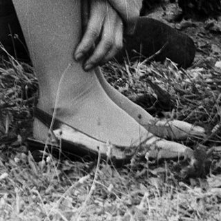 A man kneeling in grass, adjusting a camera.