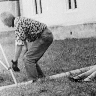 Two women gardening near a building.