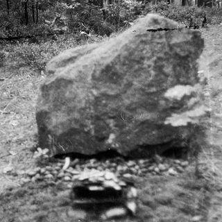 Large rock formation beside dirt path.