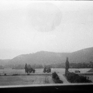 Rural landscape with road, trees, and distant hills.