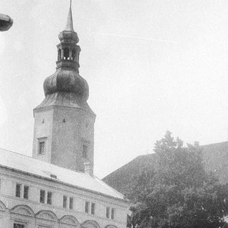 People standing near historic building with tower.