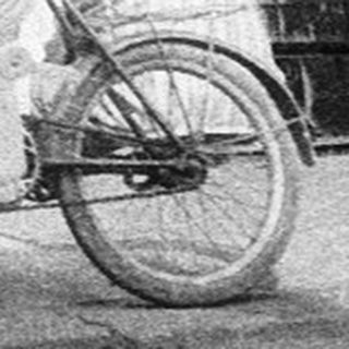 Street scene with man pushing baby stroller past crates.